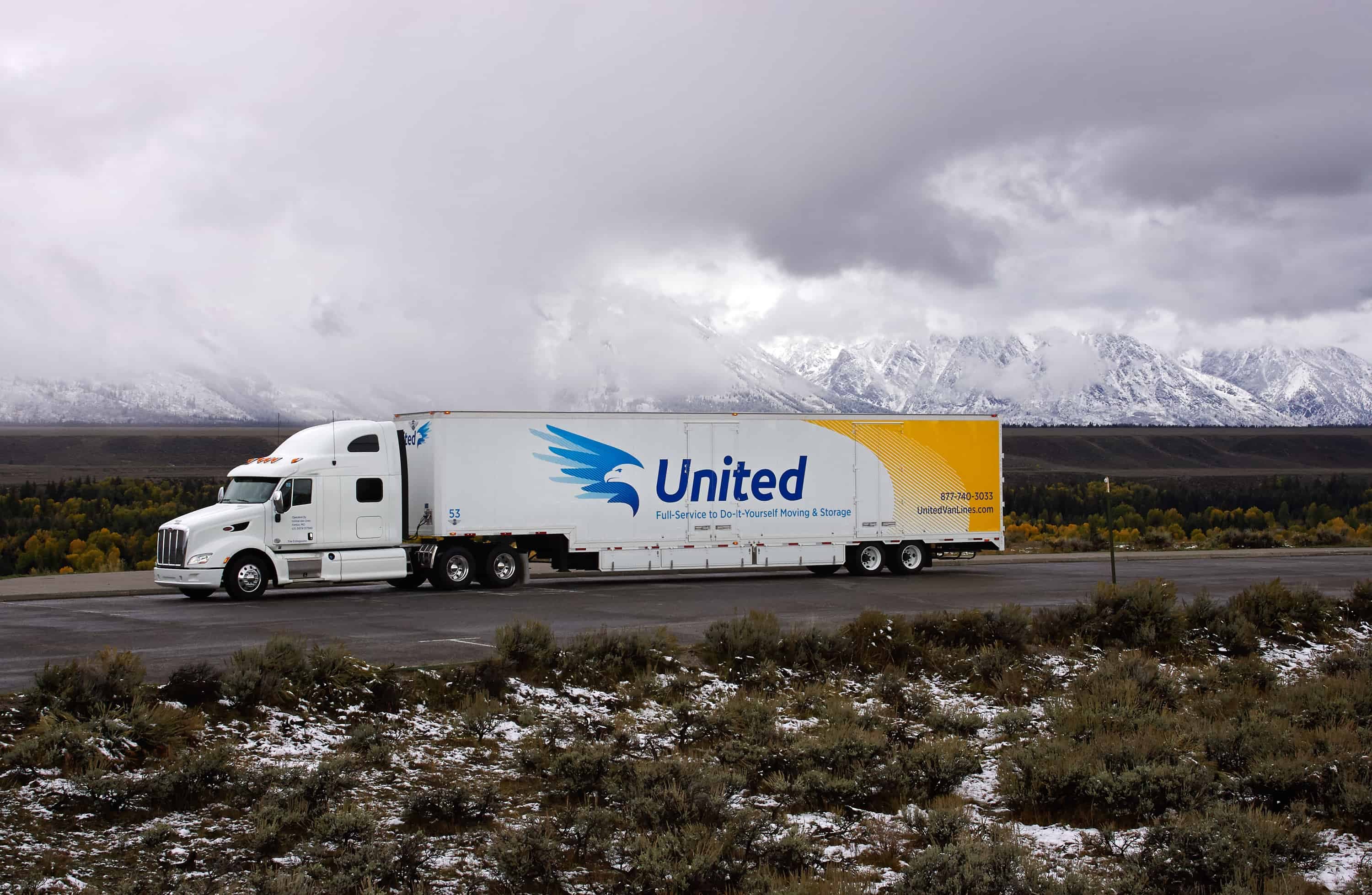 United Van Lines truck driving on a highway with snowy mountains in the background - United Van Lines®
