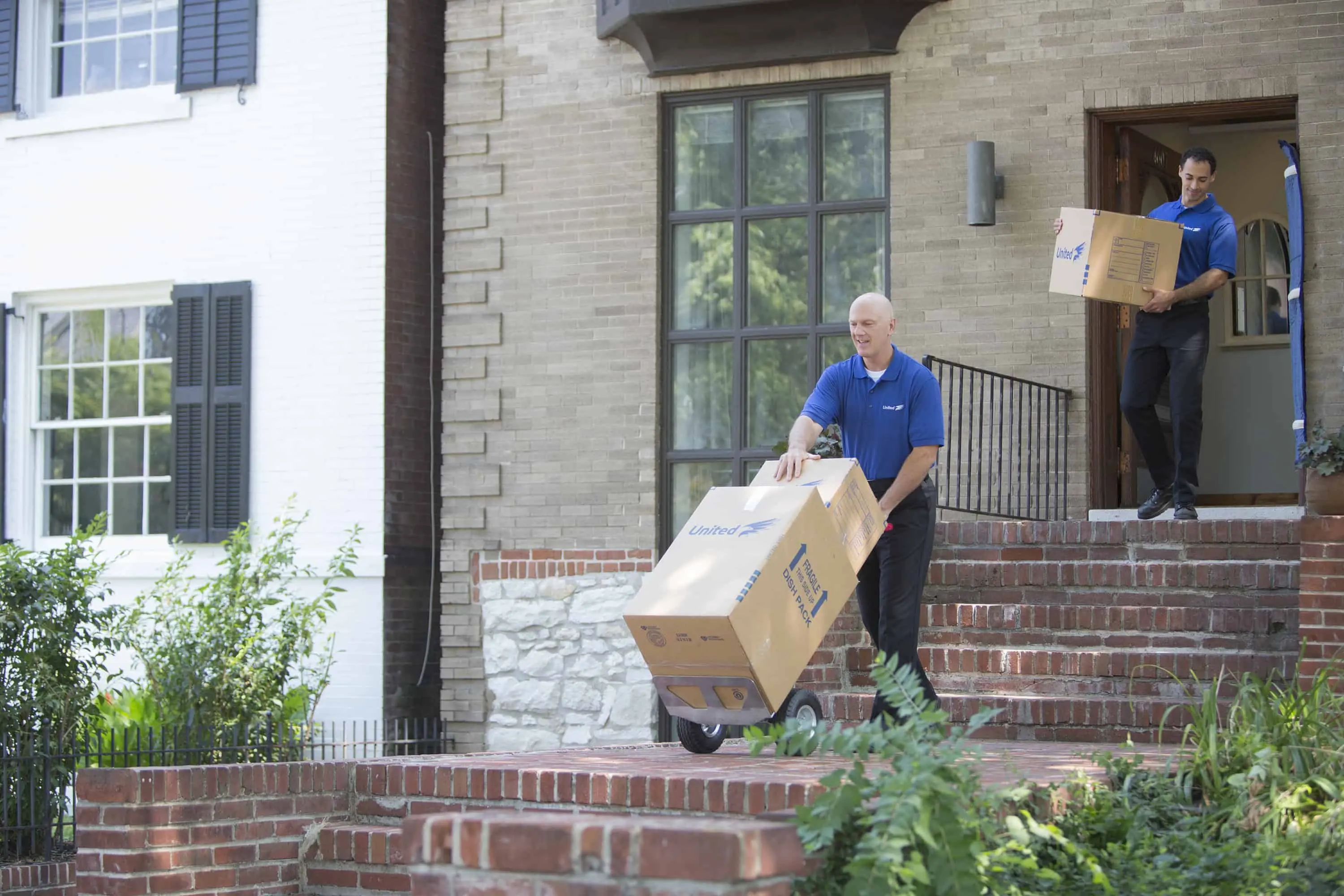 How to Avoid Surprise Moving Charges - two movers transporting boxes from a home - United Van Lines