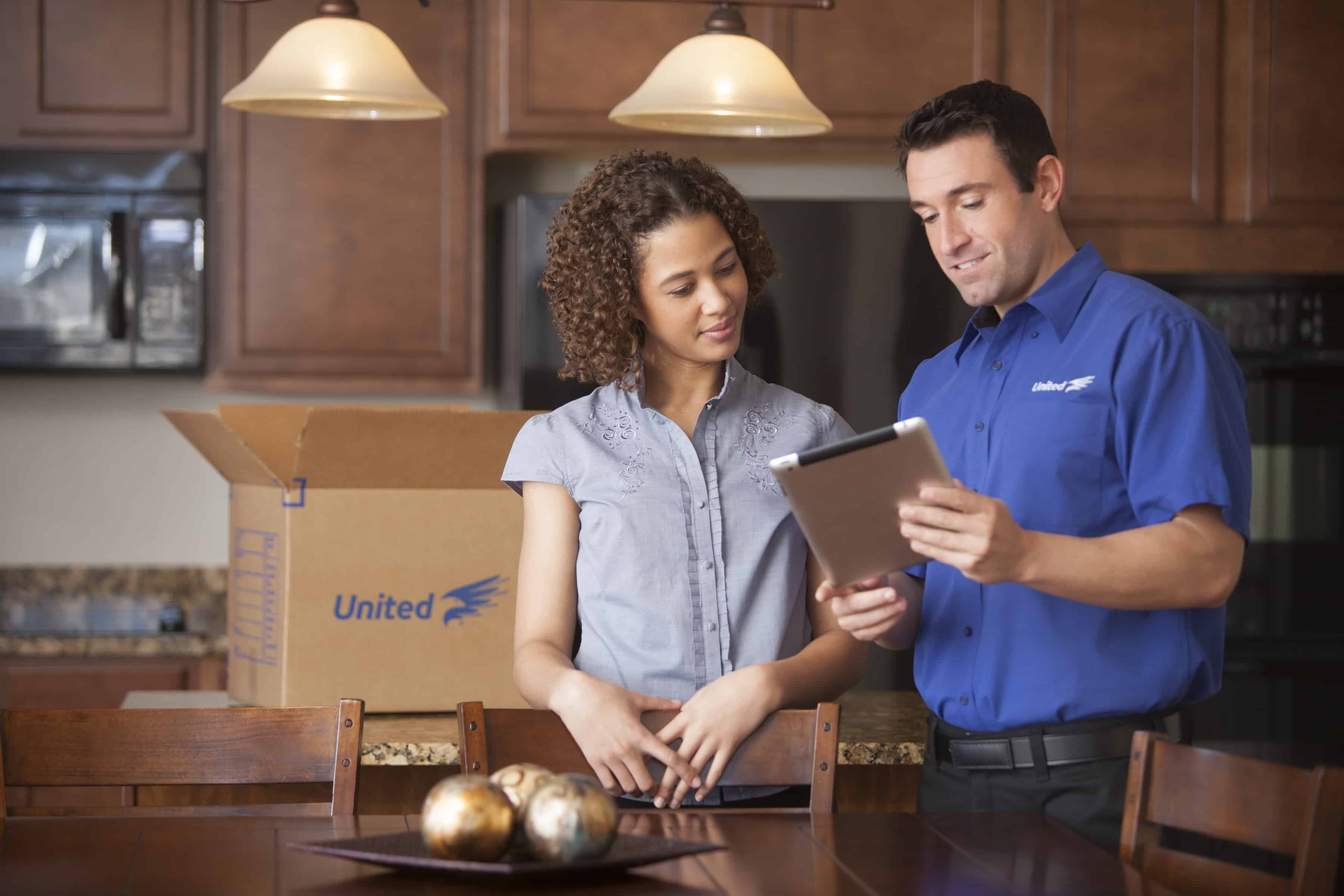 How to Understand Moving Costs - United Van Lines mover reviewing moving costs with a customer in her kitchen- United Van Lines