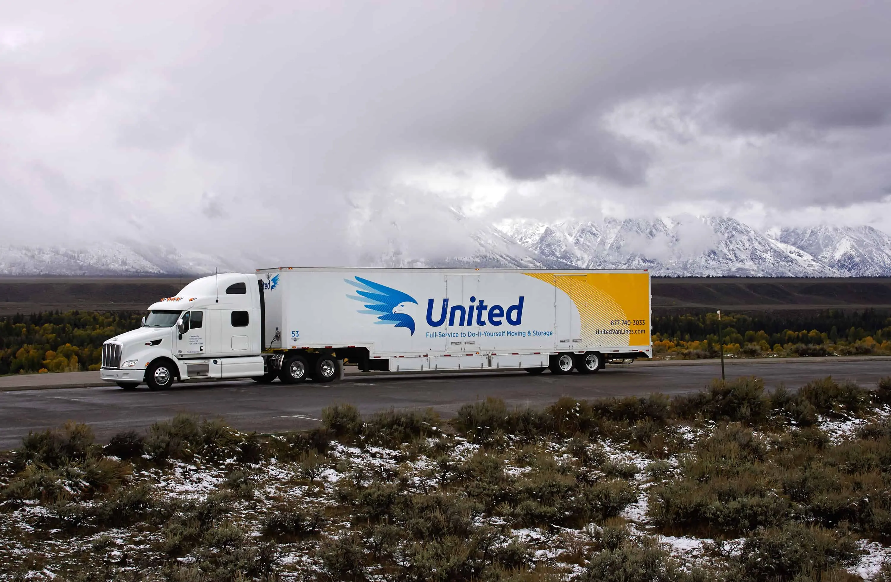 United Van Lines truck driving on a highway with snowy mountains in the background - United Van Lines®