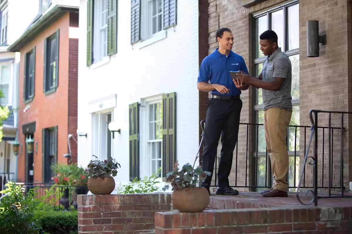 united van lines mover meets man in front of his home to discuss the bill of lading.